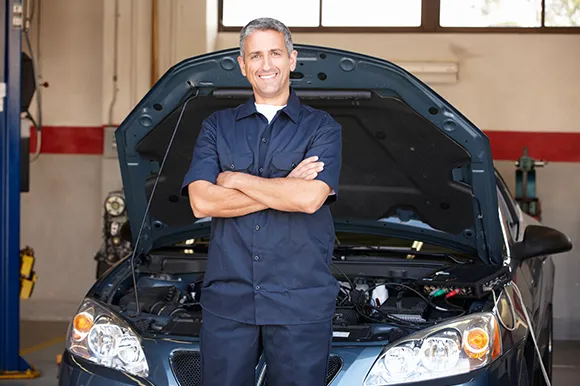 A mechanic standing in front a car