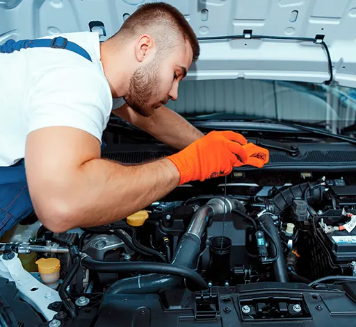 A mechanic under the hood of a car and checking its engine oil