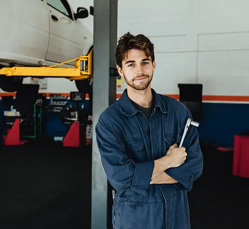 An auto mechanic holding a spanner in a car garage