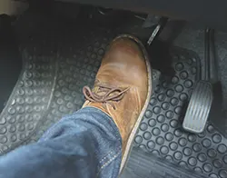 A driver placing his foot on the car's brake pedal