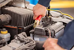 Mechanic using a jumper cable to start a stalling car engine