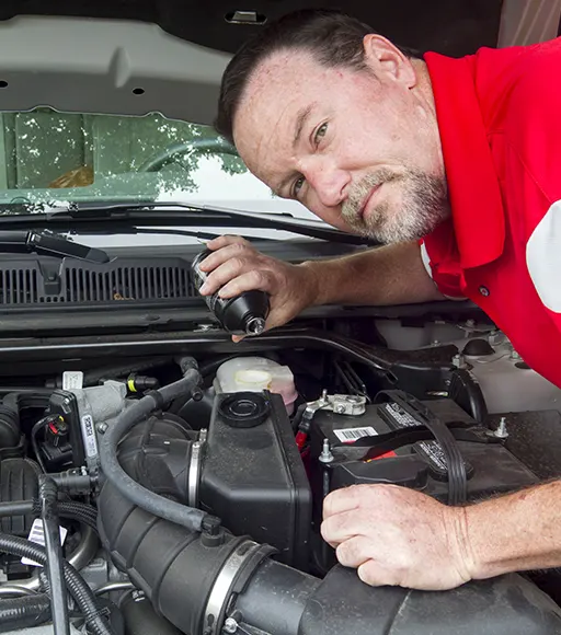 A mechanic pouring brake fluid into a car's master cylinder