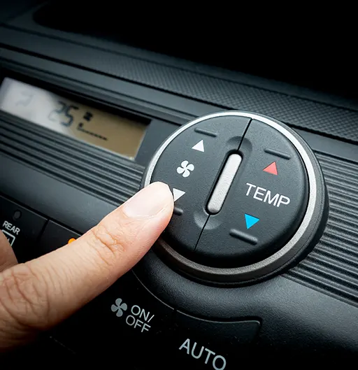 A person pressing on a car air conditioning control panel's fan speed