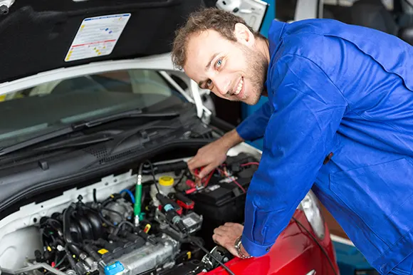 An auto technician attaching plugs to a car's battery