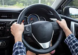 A driver's hands firmly grasping a car's steering wheel