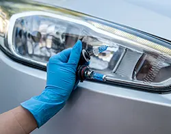 A technician holding on to a pair of car headlight bulbs