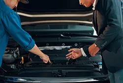 An auto mechanic explains the car's engine problem to a customer.