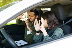 A female driver and a male driving instructor discussing inside a car