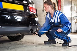 A female mechanic using an oxygen sensor to check on a car's exhaust gas