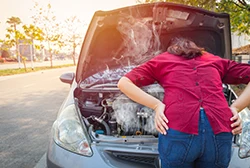 A female car owner worrying over her overheating car engine