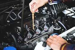 An auto mechanic checking a car's oil by removing the oil dipstick