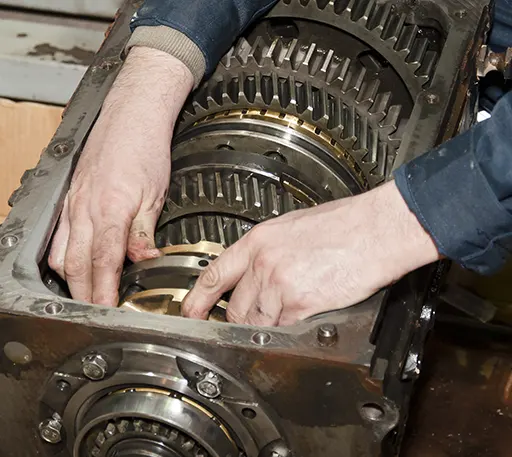 An auto mechanic working on the car's transmission