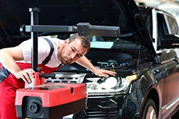 A mechanic checking and adjusting the headlights of a car